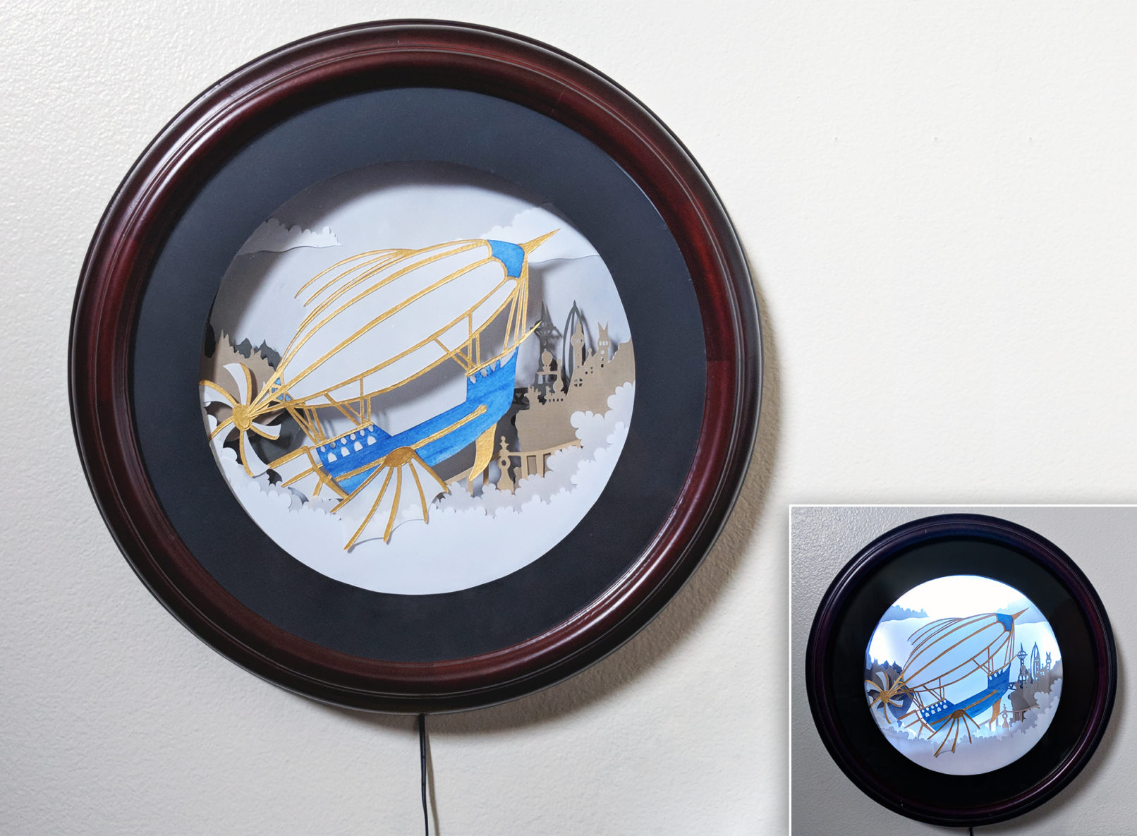 A hand cut paper art steampunk air ship with a city in the background in acircular shadowbox frame.